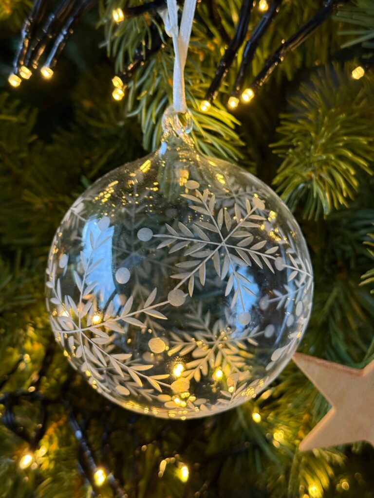 pallina di vetro con decorazioni natalizie e fondo abete